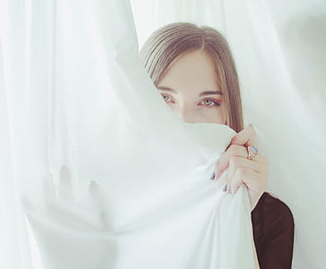woman hiding behind white window curtain thumbnail