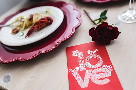 Fancy dinner with seafood pasta, crayfish and red wine by the table decorated with roses thumbnail