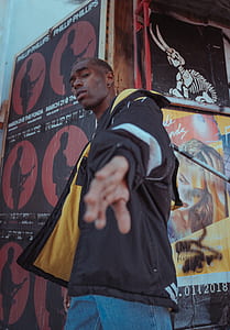 man wearing black jacket walking near the wall thumbnail