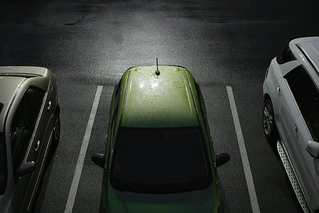 green car parked beside silver sedan during nighttime thumbnail