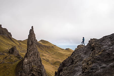 person on rocky mountain summit under white cloudy sky during daytime thumbnail