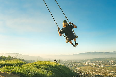 woman swinging under blue sky at daytime thumbnail