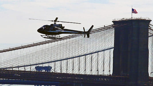 Helicopter flying by the Brooklyn Bridge in Lower Manhattan in New York City. thumbnail