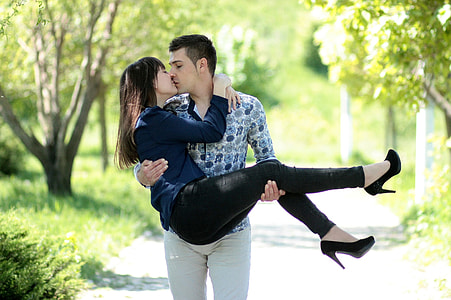 man carrying woman while kissing during daytime thumbnail