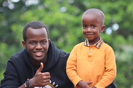Man Wearing Black Hoodie Beside Boy Wearing Orange Long-sleeved Polo Shirt thumbnail