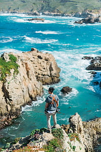 photo of man with harness standing on top of cliff facing body of water thumbnail