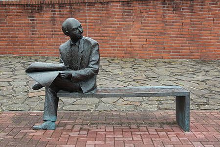 man sitting on bench holding paper statue thumbnail