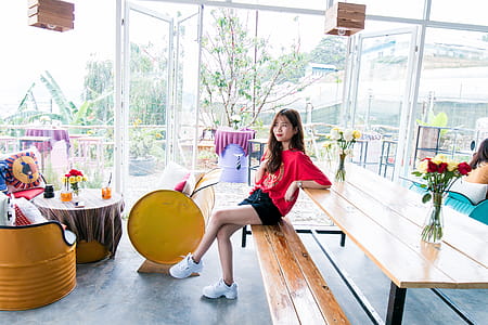 Woman in Red Crew-neck T-shirt and Blue Short Shorts Sitting on Bench thumbnail