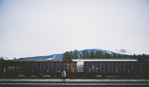 man standing on rail track near trains thumbnail