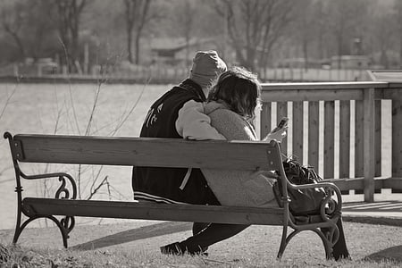 grayscale photo of man and woman sitting on waiting bench thumbnail