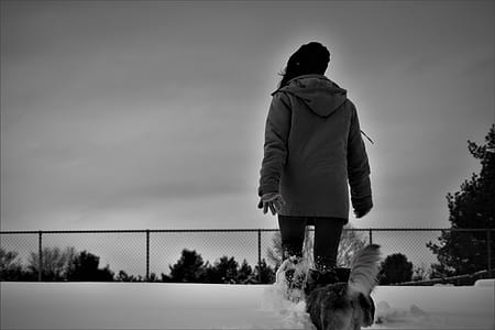 Grayscale Photo Of Person Wearing Coat Walks On Snow thumbnail