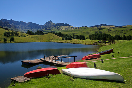 several assorted-color kayaks on green grass fields under blue calm sky thumbnail