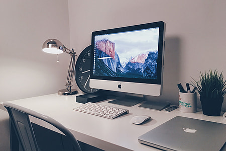 iMac computer and laptop on white office desk table thumbnail