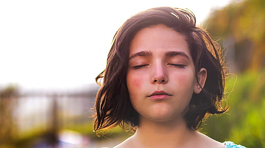 woman closing eyes selective focus photography thumbnail
