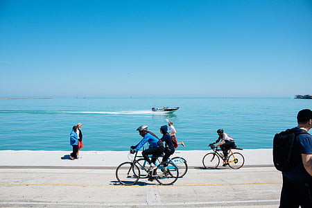 people walking and biking beside body of water thumbnail