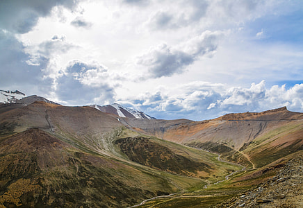 aerial photography of mountains under gray clouds and blue sky thumbnail