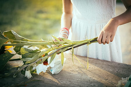 woman wearing white dress standing beside table holding flowers thumbnail