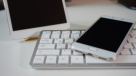 silver Samsung Android smartphone on top of Apple brand keyboard thumbnail