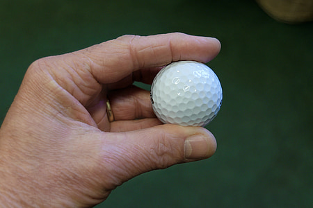 person holds white golf ball thumbnail