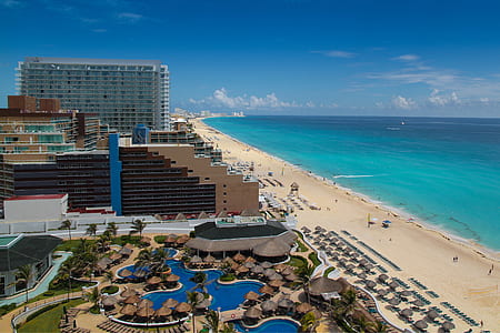 aerial photography of high rise buildings near seashore and blue body of water under blue sky thumbnail