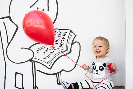 baby in gray and white top holding balloon thumbnail