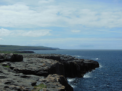 gray and brown cliff in front of body of water at daytime thumbnail