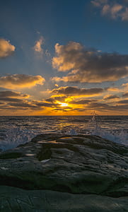 golden hour photography of cliff near body of water thumbnail