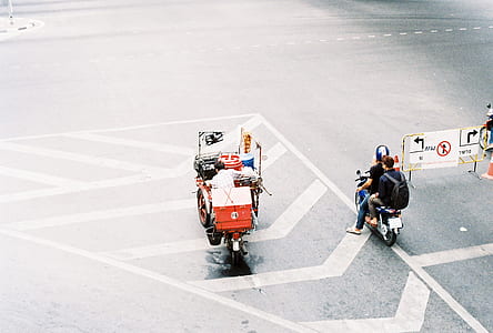 white and red auto rickshaw on concrete road beside black motor scooter thumbnail