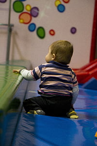 baby sitting on blue mattress thumbnail
