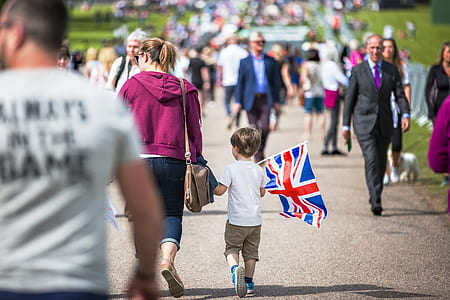 boy holding United Kingdom flag in front of crowded people thumbnail