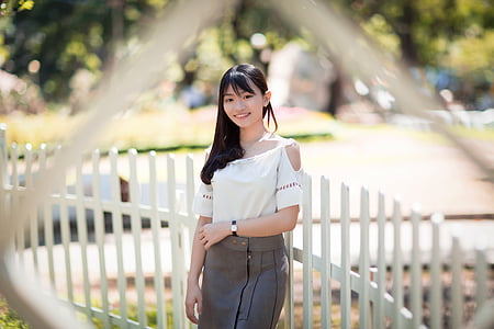 woman standing near white wooden fence at daytime thumbnail