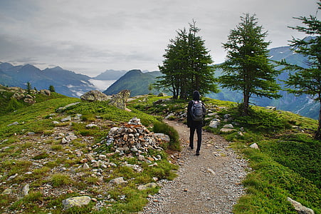 person walking on gray rocky road leading to body of water thumbnail