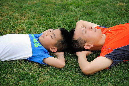man and boy lying on green grass field thumbnail