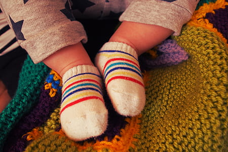 baby wearing pair of red-blue-yellow-and-white socks thumbnail