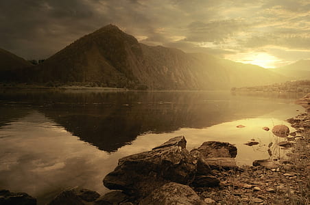 photo of calm water of lake near mountain during golden hour thumbnail