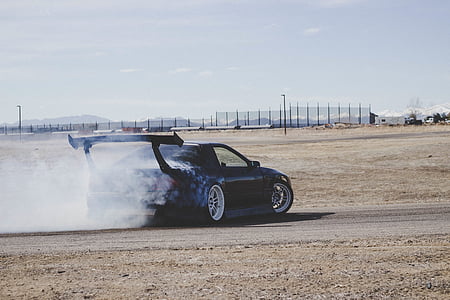 black coupe drifting on sand during daytime thumbnail