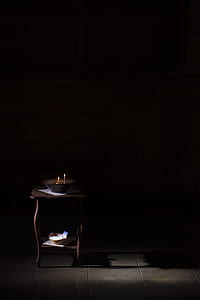 lighted candle on black bowl on brown wooden table thumbnail