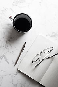half-empty black and white ceramic mug near notebook thumbnail