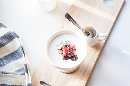 white ceramic cup filled with white liquid on beige wooden chopping board thumbnail