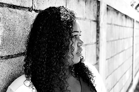 grayscale photo of woman standing beside the wall thumbnail