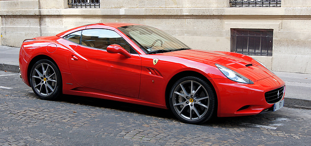 red Ferrari coupe parked near beige building thumbnail