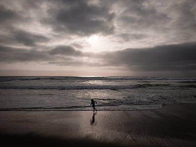 silhouette of toddler standing beside sea shore during daytime thumbnail