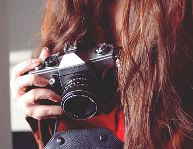 woman holding gray Praktica camera thumbnail