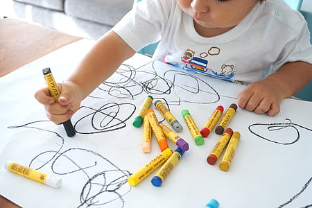 toddler holding crayon in front of white printing paper thumbnail