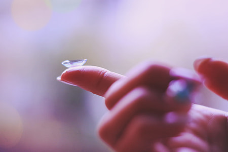 contact lens on tip of persons index finger thumbnail