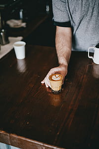 person touching glass cup with latte art thumbnail