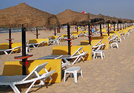 white lounger chair with patio umbrella on seashore thumbnail