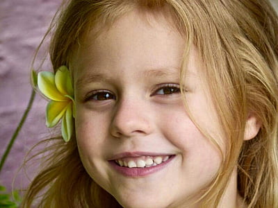 smiling girl with yellow plumeria flower on her ear thumbnail