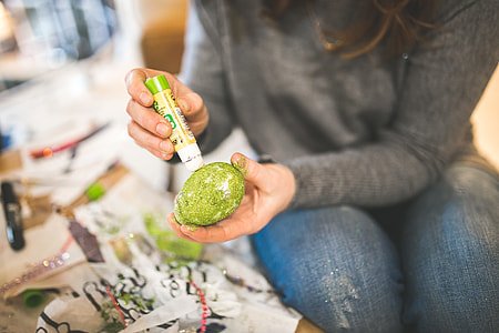photo of woman in gray long sleeve top and blue jeans holding green coloring pen and egg thumbnail
