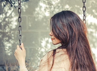 woman riding swing near wall during day thumbnail